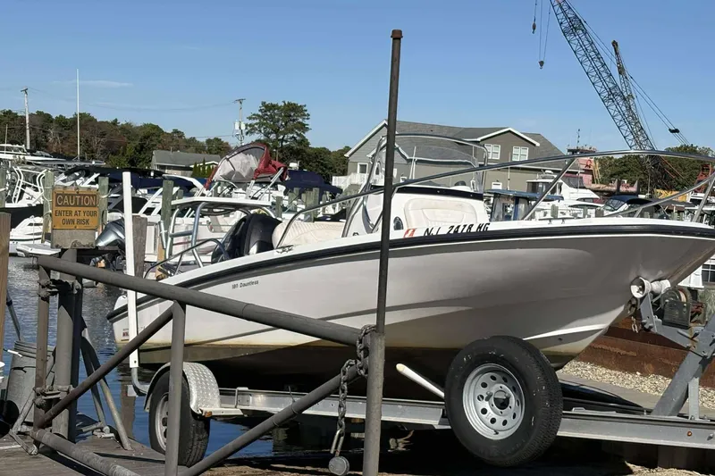 Slide: The Image of 2011 Boston Whaler 180 Dauntless on trailer at marina, caution sign visible. - 5