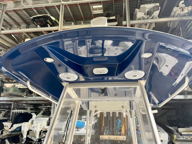 Slide: The Image of 2018 Cobia 301 Center Console boat in storage, blue T-top with mounted speakers. - 9