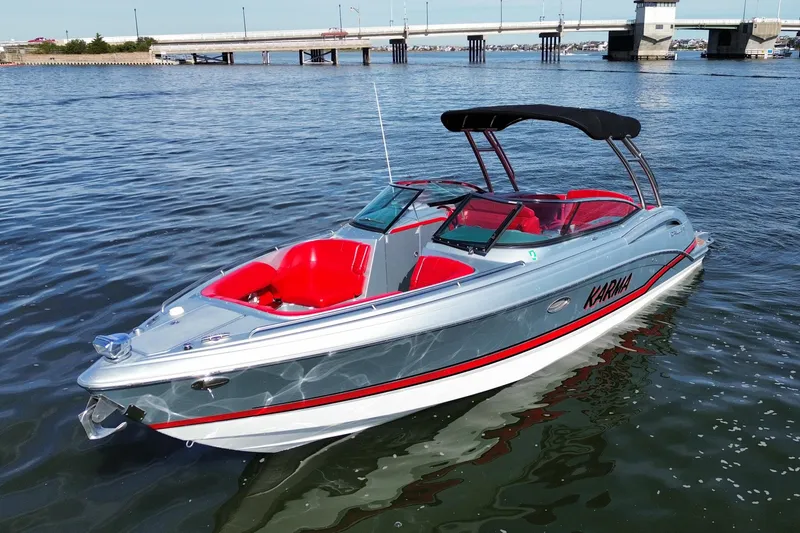 The Image of 2014 Formula 310 Bowrider boat with red interior on calm water near a bridge. - 0