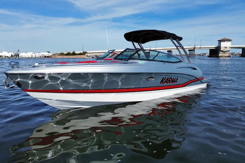 Slide: The Image of 2014 Formula 310 Bowrider boat named "Karma" on calm water near a bridge. - 10