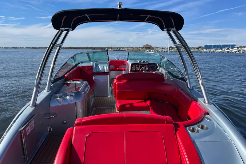 Slide: The Image of 2014 Formula 310 Bowrider with red seating, cruising on a calm lake under a clear sky. - 29