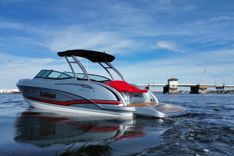 Slide: The Image of 2014 Formula 310 Bowrider boat on water, under clear blue sky near a bridge. - 4