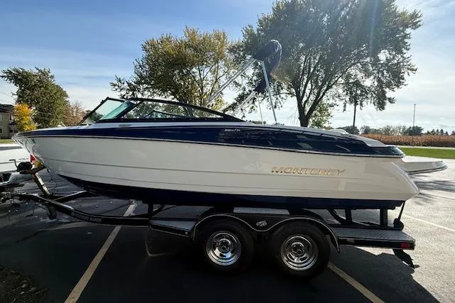 Slide: The Image of 2018 Monterey 224FS boat on trailer, parked outdoors with trees in background. - 3