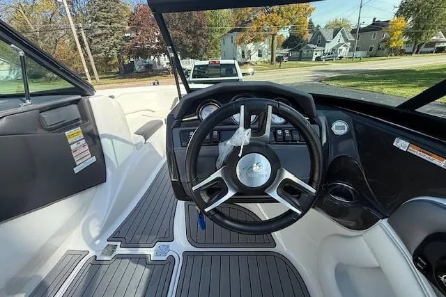Slide: The Image of 2018 Monterey 224FS boat interior with steering wheel and captain's seat, parked outdoors. - 8