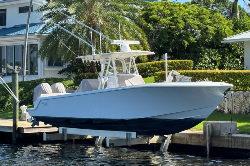 Slide: The Image of 2023 SeaVee 340Z boat docked, surrounded by lush greenery and waterfront homes. - 0