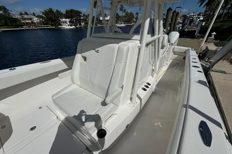 Slide: The Image of 2023 SeaVee 340Z boat with white seating, docked by a waterfront. - 13