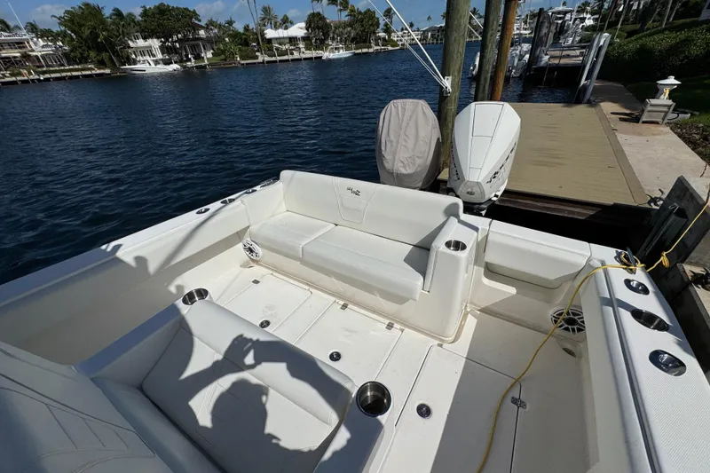 Slide: The Image of 2023 SeaVee 340Z boat interior with seating, docked by waterfront homes. - 7