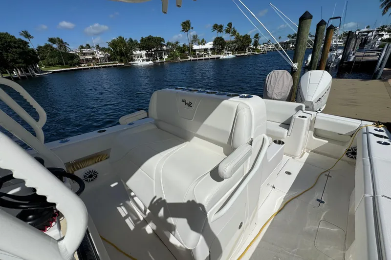 Slide: The Image of 2023 SeaVee 340Z boat interior with white seating, docked by a scenic waterfront. - 8