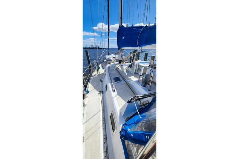 Slide: The Image of 1980 Nordic 44 sailboat docked, featuring blue sails and clear sky background. - 12