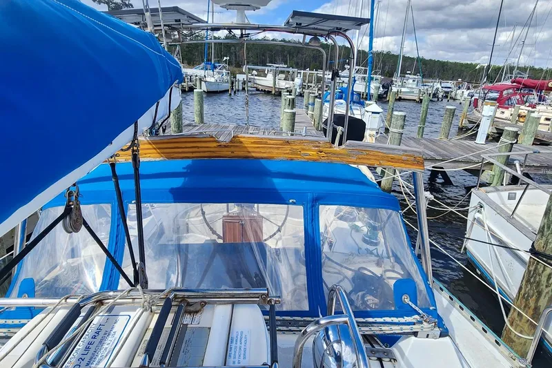 Slide: The Image of 1980 Nordic 44 sailboat docked at marina, featuring blue canopy and wooden accents. - 15