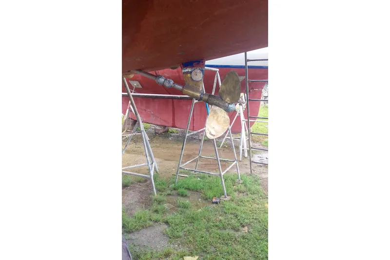 Slide: The Image of 1980 Nordic 44 sailboat propeller and rudder on stands, outdoor setting. - 36