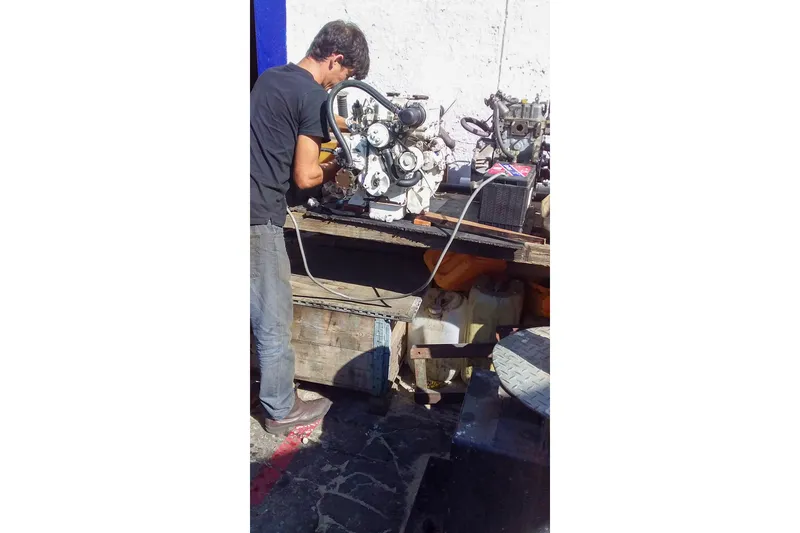 Slide: The Image of Man repairing Nordic 44 engine, 1980 model, outdoors on a sunny day. - 43