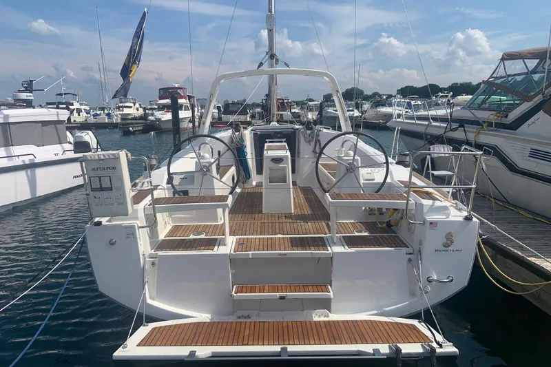 Slide: The Image of 2016 Beneteau Oceanis 38 sailboat docked at marina, showcasing spacious deck and dual steering wheels. - 1