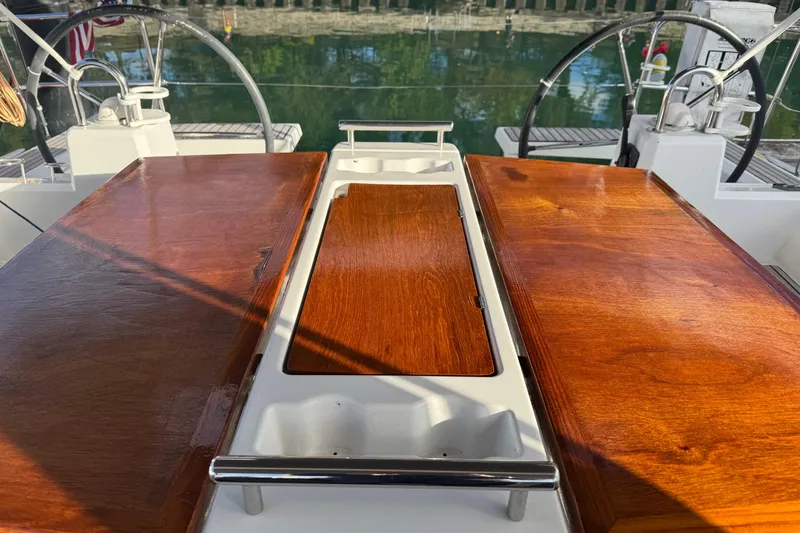 Slide: The Image of Cockpit of 2016 Beneteau Oceanis 38 sailboat with polished wooden table and dual steering wheels. - 10