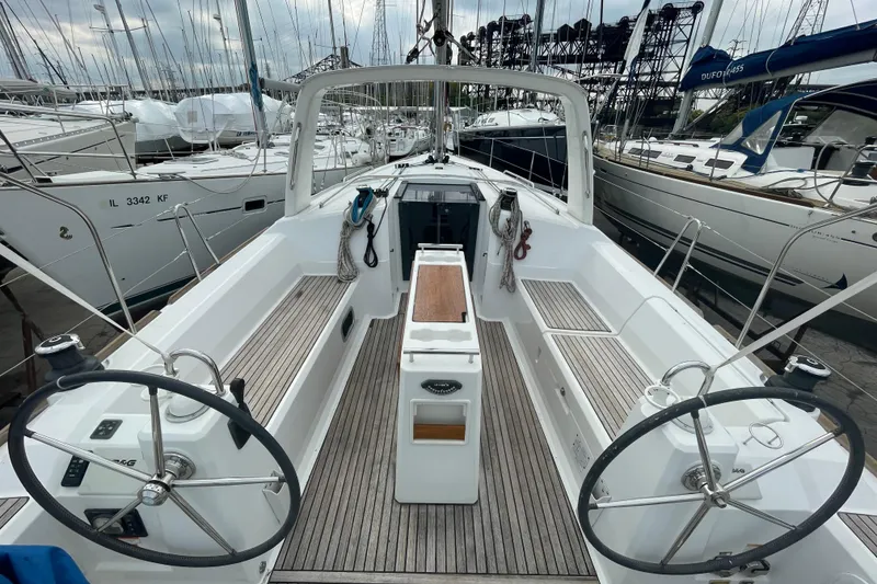Slide: The Image of 2016 Beneteau Oceanis 38 sailboat cockpit with dual steering wheels, docked among other yachts. - 8