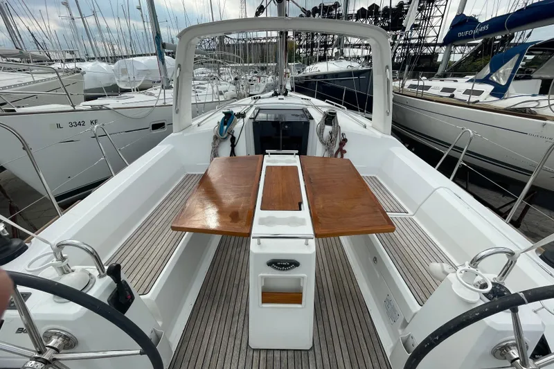 Slide: The Image of Cockpit view of 2016 Beneteau Oceanis 38 sailboat with wooden table and dual steering wheels. - 9