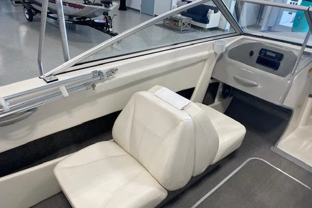 Slide: The Image of 2012 Bayliner 195 Discovery boat interior with white seating and dashboard. - 11