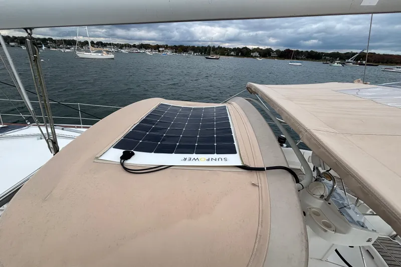 Slide: The Image of Beneteau Oceanis 411 sailboat with solar panel on deck, anchored in a scenic harbor. - 16