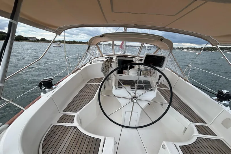 Slide: The Image of 2002 Beneteau Oceanis 411 sailboat cockpit with steering wheel, docked on a scenic waterfront. - 17