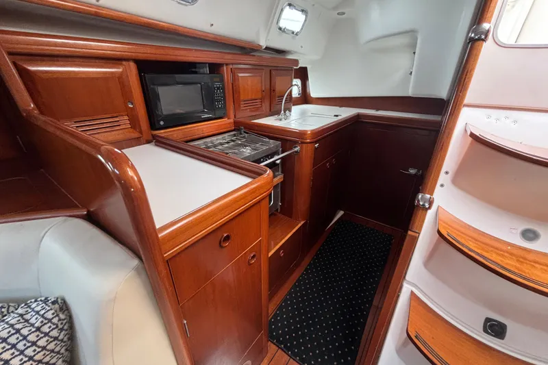 Slide: The Image of Luxurious 2002 Beneteau Oceanis 411 yacht interior with wood cabinetry and modern kitchen amenities. - 2