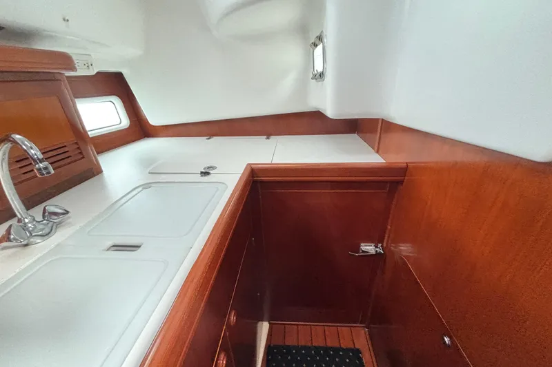 Slide: The Image of Interior of 2002 Beneteau Oceanis 411 yacht, featuring a sleek kitchen with wooden cabinetry. - 28