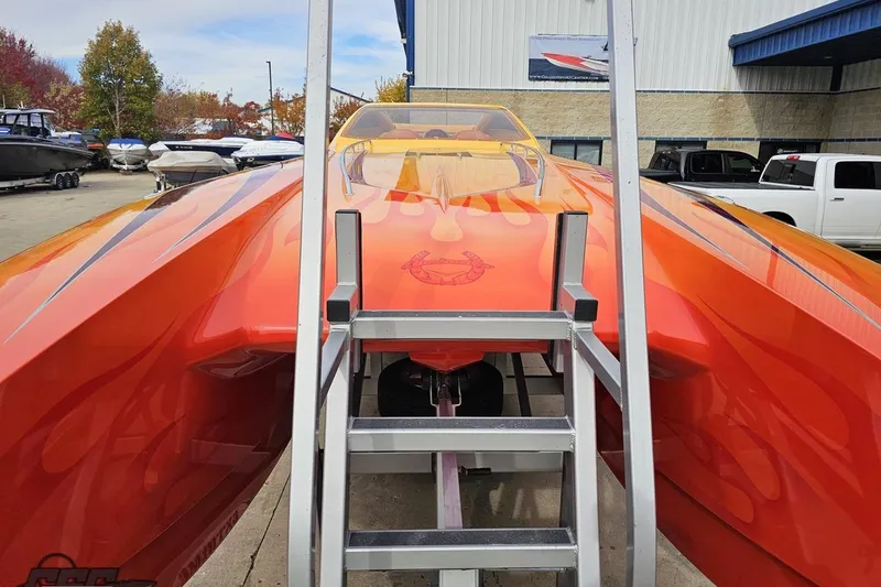 Slide: The Image of 2008 Eliminator 36 Daytona Coupe in vibrant orange, parked outdoors with ladder access. - 25