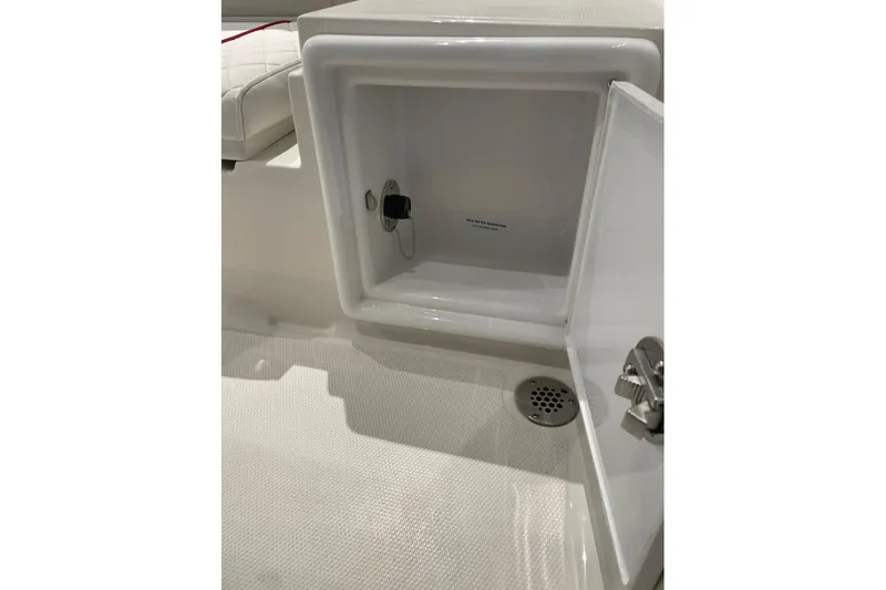 Slide: The Image of Open storage compartment on 2026 Ranger 2510 Bay boat, featuring a drain and latch. - 17