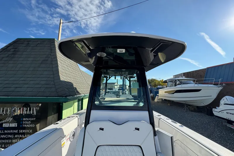 Slide: The Image of 2026 Stingray 253 CC boat, center console view, displayed at a marina under a clear blue sky. - 23