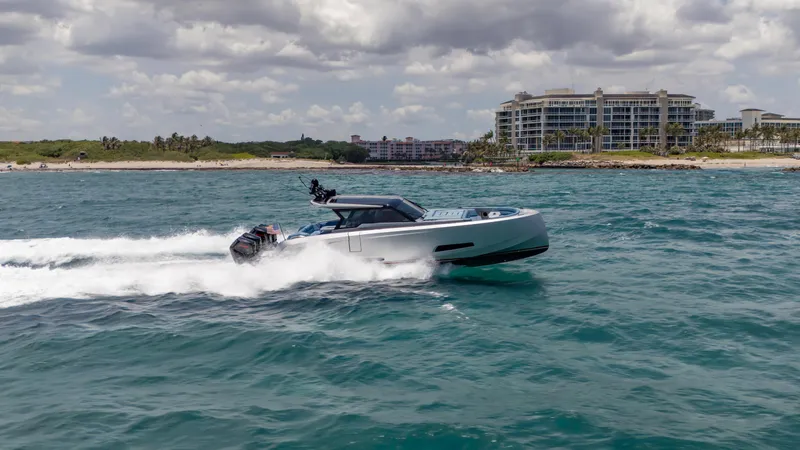 Slide: The Image of 2023 Vanquish Yachts VQ45 cruising on ocean near luxury beachfront buildings. - 25