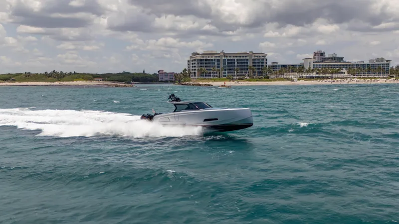 Slide: The Image of 2023 Vanquish Yachts VQ45 cruising on ocean near coastal buildings under cloudy sky. - 27