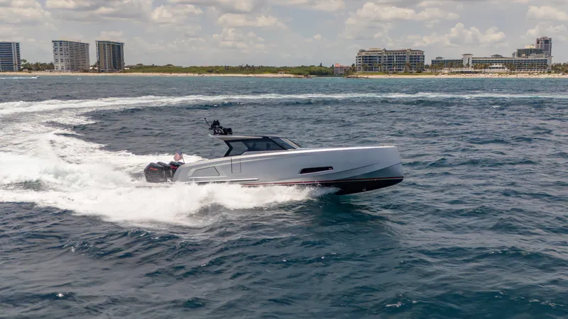 Slide: The Image of 2023 Vanquish Yachts VQ45 cruising on open water near a coastal cityscape. - 4