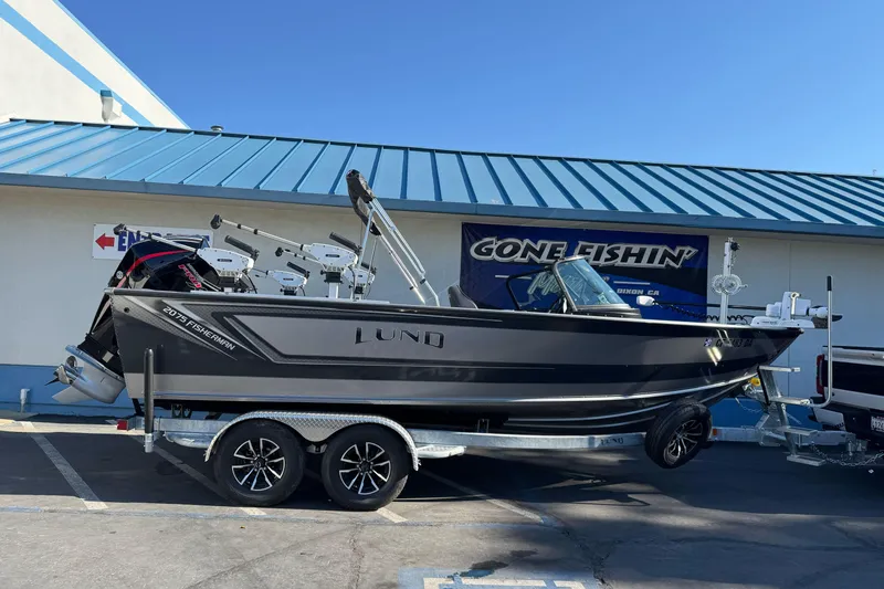 The Image of 2026 Lund 2075 Fisherman boat on trailer outside a store with blue roof. - 1