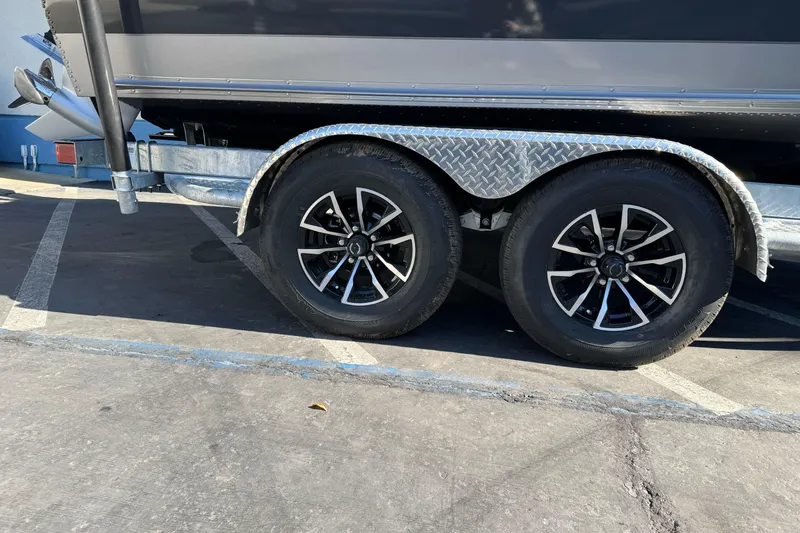 Slide: The Image of Trailer wheels of a 2026 Lund 2075 Fisherman boat in a parking lot. - 2