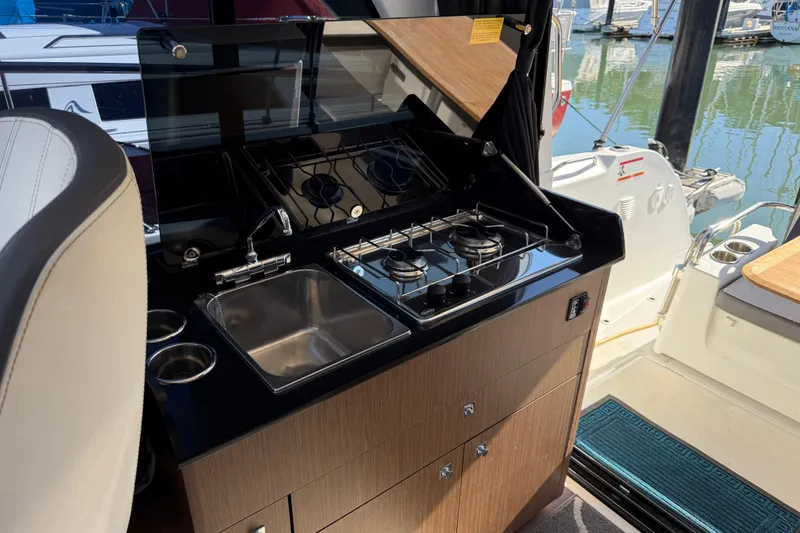Slide: The Image of Interior of 2021 Beneteau Antares 9 boat with compact kitchen and stove. - 12