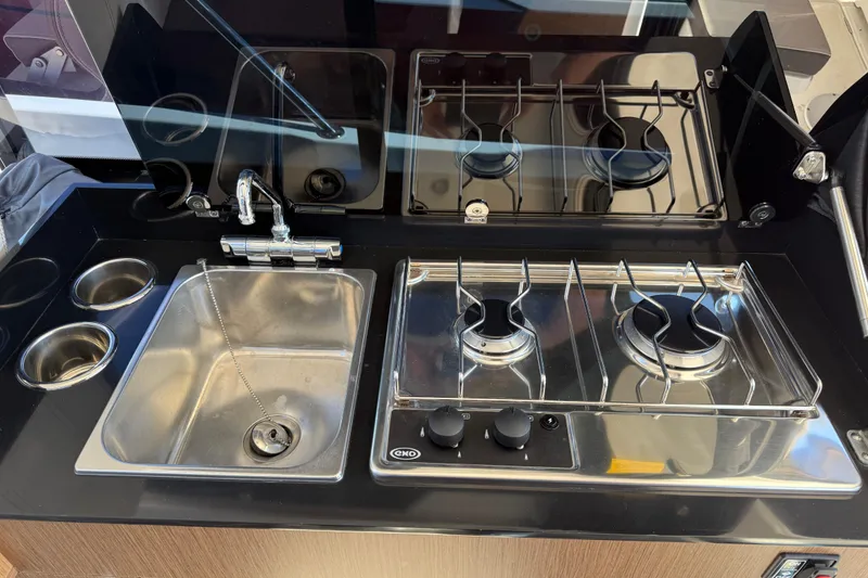 Slide: The Image of Modern kitchen area in a 2021 Beneteau Antares 9 boat, featuring a sink and dual-burner stove. - 13
