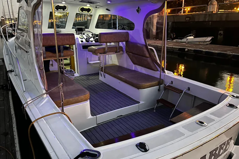 The Image of 1999 Mainship Pilot 30 boat interior with seating, docked at night. - 1