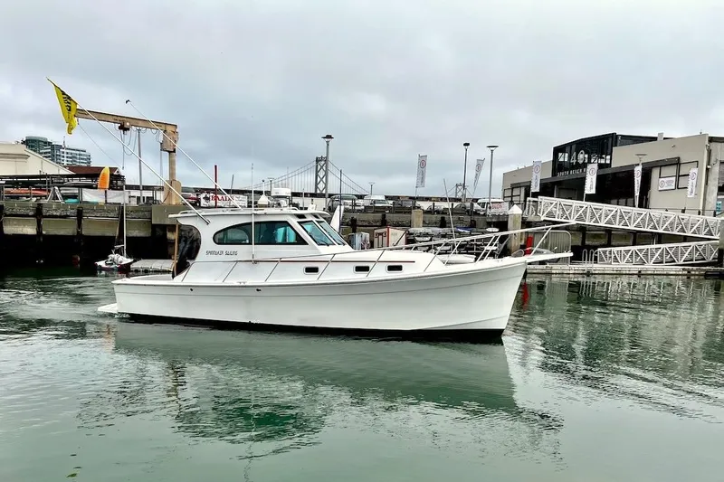 Slide: The Image of 1999 Mainship Pilot 30 boat docked in a marina with overcast skies. - 13