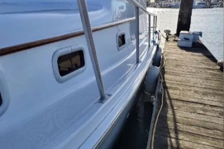 Slide: The Image of 1999 Mainship Pilot 30 docked, showcasing sleek white hull and wooden railings. - 26