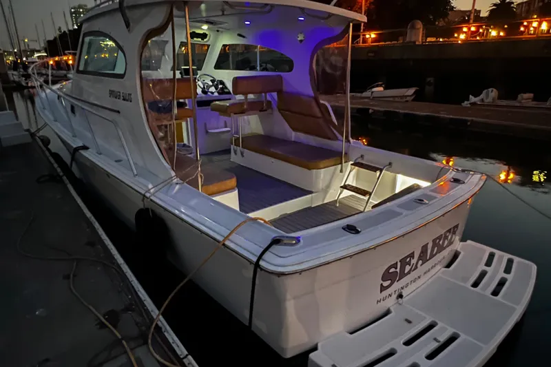 Slide: The Image of 1999 Mainship Pilot 30 docked at sunset, featuring illuminated interior and spacious deck. - 3