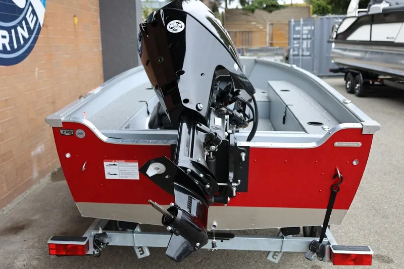 Slide: The Image of 2026 Lund 1400 Fury Tiller boat with outboard motor, red and silver design, on a trailer. - 3