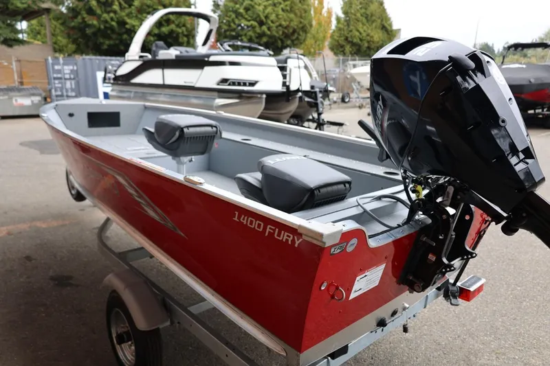 Slide: The Image of 2026 Lund 1400 Fury Tiller boat, red exterior, parked on a trailer. - 4