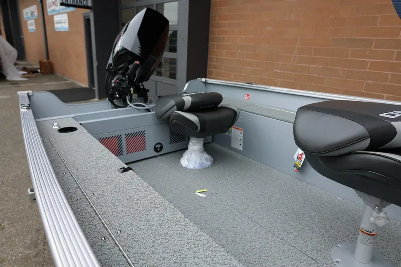 Slide: The Image of 2026 Lund 1400 Fury Tiller boat interior with seating and motor, parked outside a building. - 7