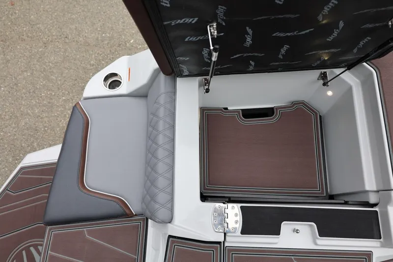Slide: The Image of 2026 Tigé 22RZX boat interior storage compartment with cushioned seating and cup holder. - 51