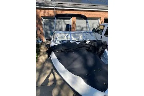 Slide: The Image of 2013 Bayliner 170 Bowrider boat with cover, parked near a garage. - 2