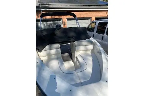 Slide: The Image of 2013 Bayliner 170 Bowrider boat with covered seating, parked near a garage. - 3