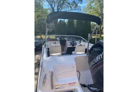 Slide: The Image of 2013 Bayliner 170 Bowrider with Mercury engine, parked outdoors under a clear sky. - 7