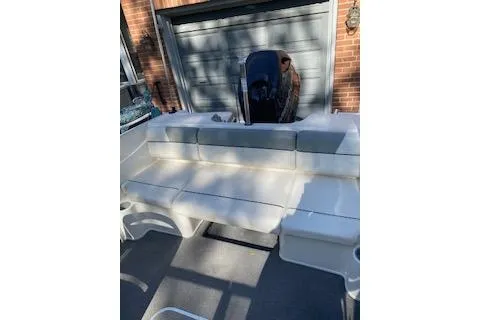 Slide: The Image of 2013 Bayliner 170 Bowrider boat with white seating, parked near a garage. - 9