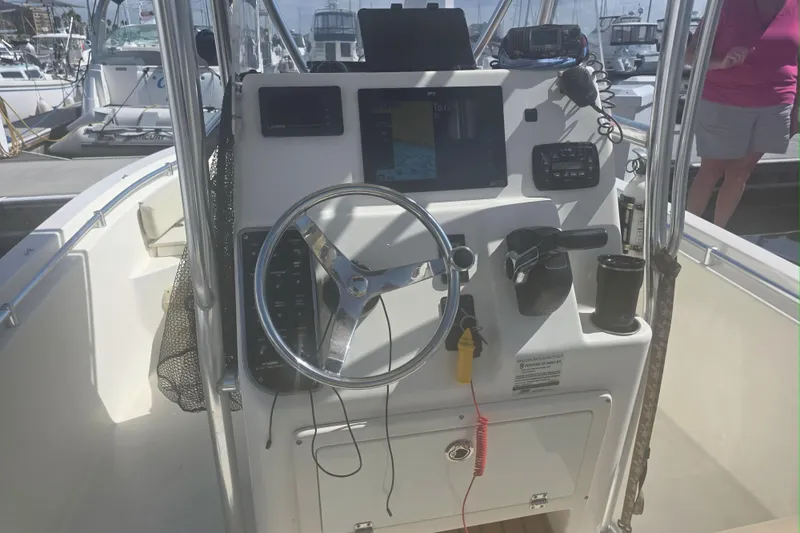 Slide: The Image of 2017 Cobia T-Top boat console with steering wheel and navigation equipment at marina. - 2