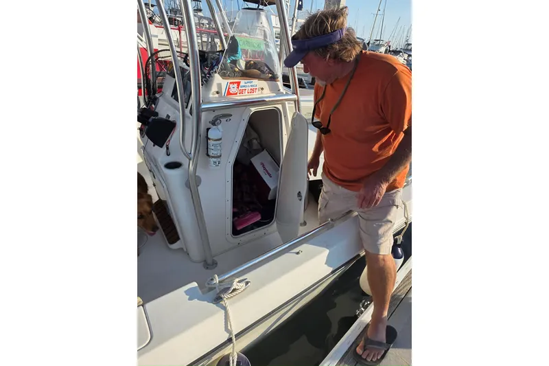 Slide: The Image of Man on 2017 Cobia T-Top boat at marina, inspecting cabin area. - 4
