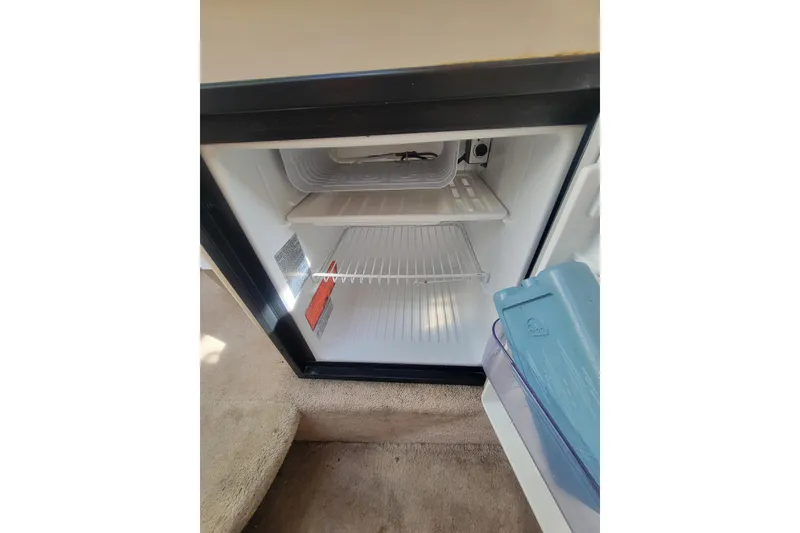 Slide: The Image of Open mini fridge inside 2000 Sea Ray 260 Sundancer boat, showing empty shelves. - 12